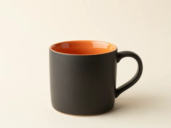 A matte charcoal mug with an orange rim stripe on a plain background